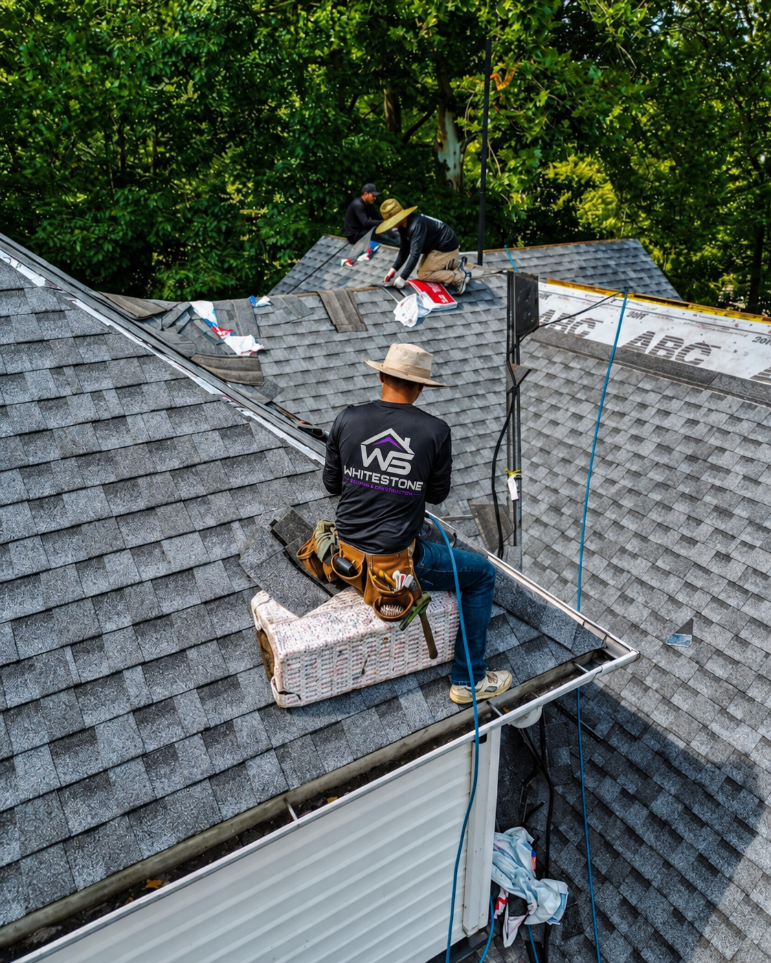 Roofing crew working on a shingle roof, wearing Whitestone branding